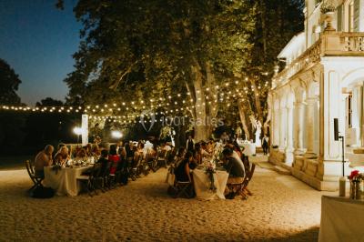 Vue aérienne d'une grande maison de style provençal avec des tables dressées pour un événement en extérieur.