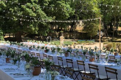 Vue aérienne d'une grande maison de style provençal avec des tables dressées pour un événement en extérieur.