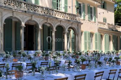 Vue aérienne d'une grande maison de style provençal avec des tables dressées pour un événement en extérieur.