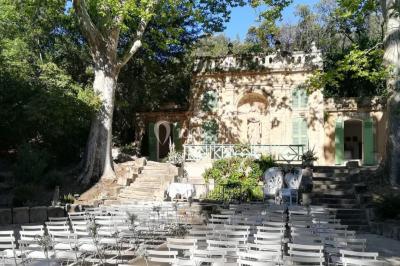 Vue aérienne d'une grande maison de style provençal avec des tables dressées pour un événement en extérieur.