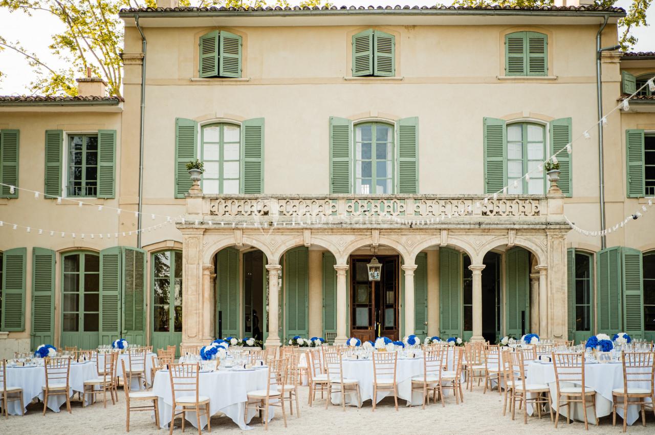Façade d'un bâtiment ancien avec tables et chaises disposées en extérieur pour un événement.