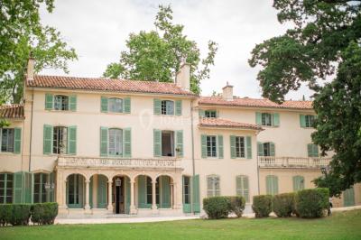 Vue aérienne d'une grande maison de style provençal avec des tables dressées pour un événement en extérieur.