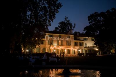 Vue aérienne d'une grande maison de style provençal avec des tables dressées pour un événement en extérieur.