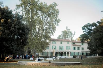 Vue aérienne d'une grande maison de style provençal avec des tables dressées pour un événement en extérieur.