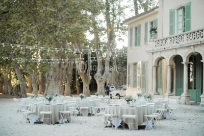 Vue aérienne d'une grande maison de style provençal avec des tables dressées pour un événement en extérieur.