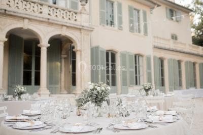 Vue aérienne d'une grande maison de style provençal avec des tables dressées pour un événement en extérieur.