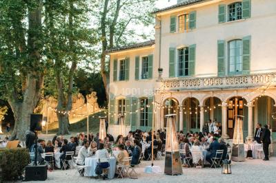 Vue aérienne d'une grande maison de style provençal avec des tables dressées pour un événement en extérieur.