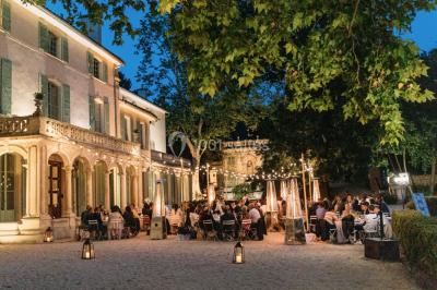 Vue aérienne d'une grande maison de style provençal avec des tables dressées pour un événement en extérieur.