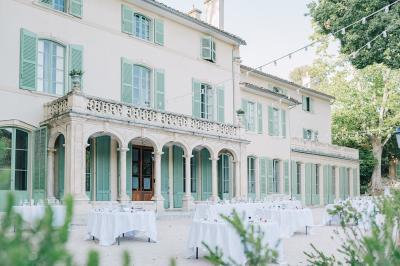 Vue aérienne d'une grande maison de style provençal avec des tables dressées pour un événement en extérieur.