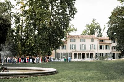Vue aérienne d'une grande maison de style provençal avec des tables dressées pour un événement en extérieur.