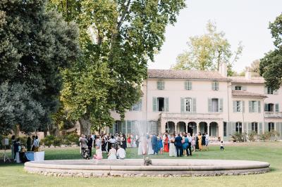 Vue aérienne d'une grande maison de style provençal avec des tables dressées pour un événement en extérieur.