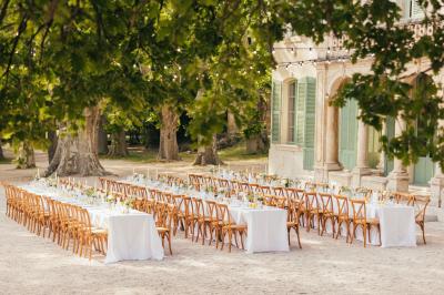 Vue aérienne d'une grande maison de style provençal avec des tables dressées pour un événement en extérieur.