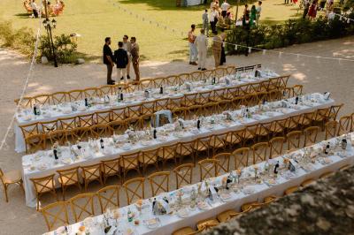 Vue aérienne d'une grande maison de style provençal avec des tables dressées pour un événement en extérieur.