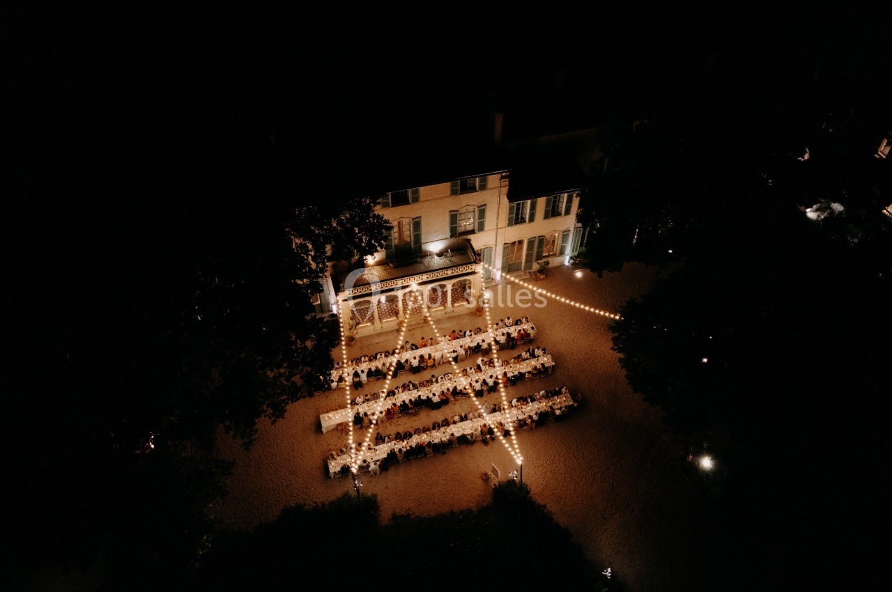 Location salle Marseille 14 (Bouches-du-Rhône) - Bastide de Toursainte #2 Vue aérienne nocturne d'une réception en extérieur, avec des tables alignées sous des guirlandes lumineuses près d'un…