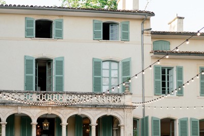 Miniature Location salle Marseille 14 (Bouches-du-Rhône) - Bastide de Toursainte #92 Chaises transparentes disposées en rangées sur une allée blanche, entourées d'arbres dans un cadre extérieur.