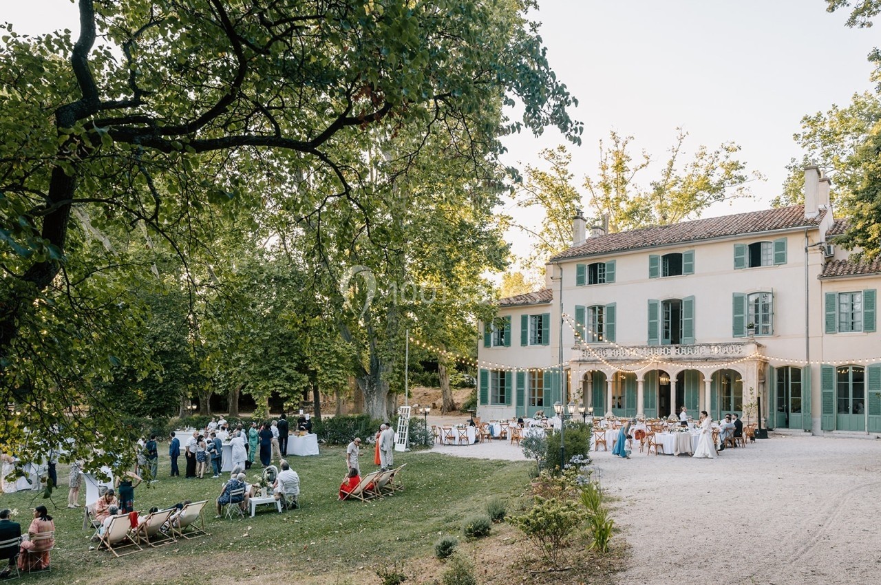 Location salle Marseille 14 (Bouches-du-Rhône) - Bastide de Toursainte #1 Jardin d'une grande maison avec des invités rassemblés pour un événement, tables dressées et guirlandes lumineuses.