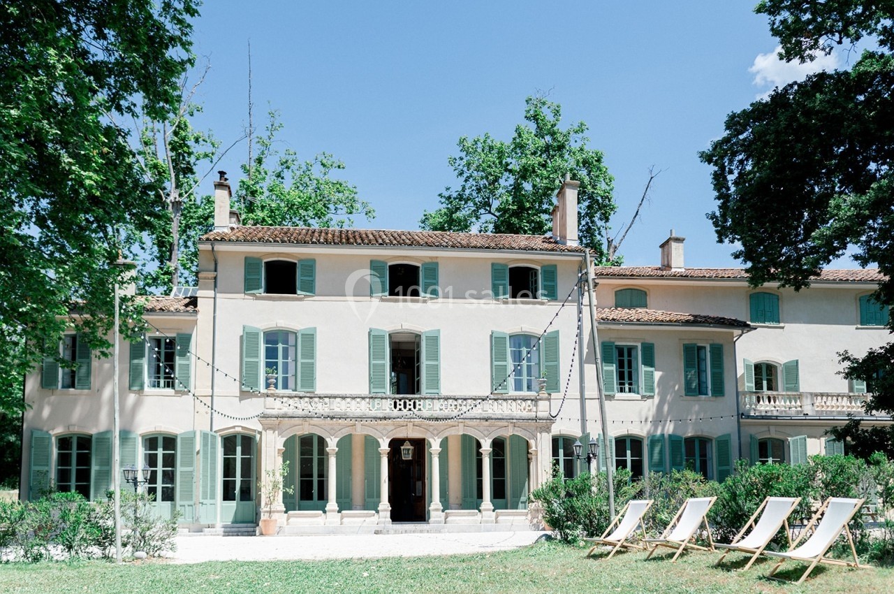 Location salle Marseille 14 (Bouches-du-Rhône) - Bastide de Toursainte #93 Façade d'une grande maison provençale avec volets verts, entourée de végétation et de chaises longues sur une pelouse.