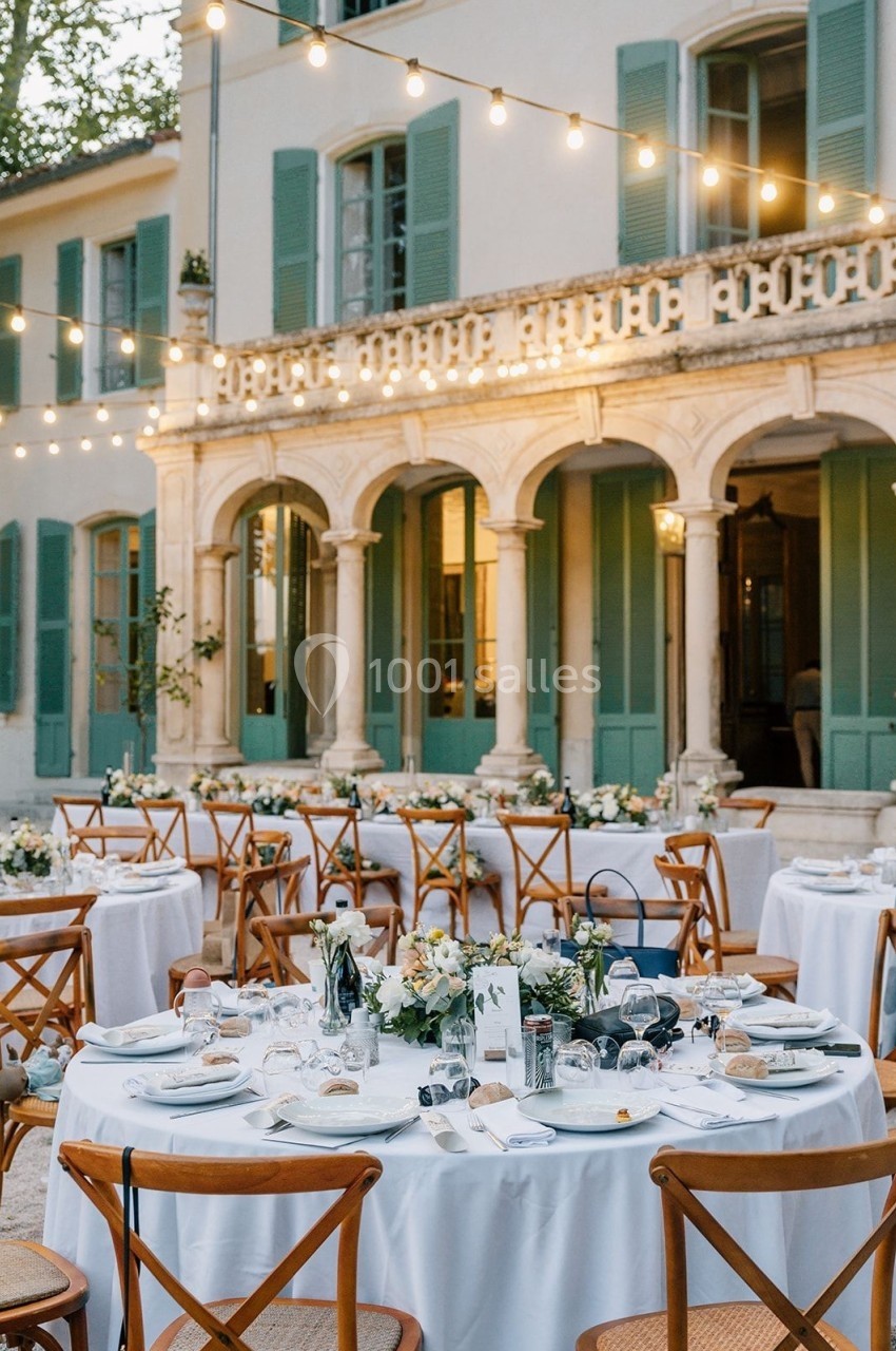 Location salle Marseille 14 (Bouches-du-Rhône) - Bastide de Toursainte #95 Tables de réception élégamment dressées en extérieur, devant une bâtisse aux volets verts, éclairée par des guirlandes…