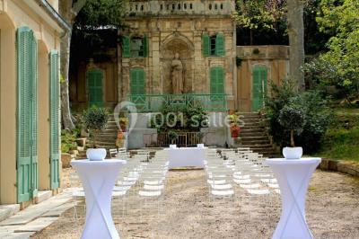 Vue aérienne d'une grande maison de style provençal avec des tables dressées pour un événement en extérieur.