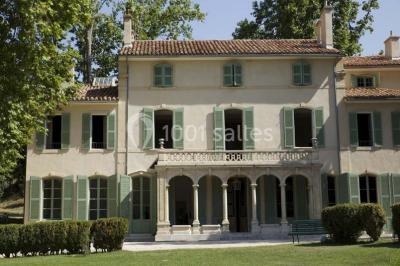 Vue aérienne d'une grande maison de style provençal avec des tables dressées pour un événement en extérieur.