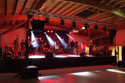 Vue d'une prairie verdoyante avec un grand arbre à gauche et des bâtiments ruraux sous un ciel dégagé.