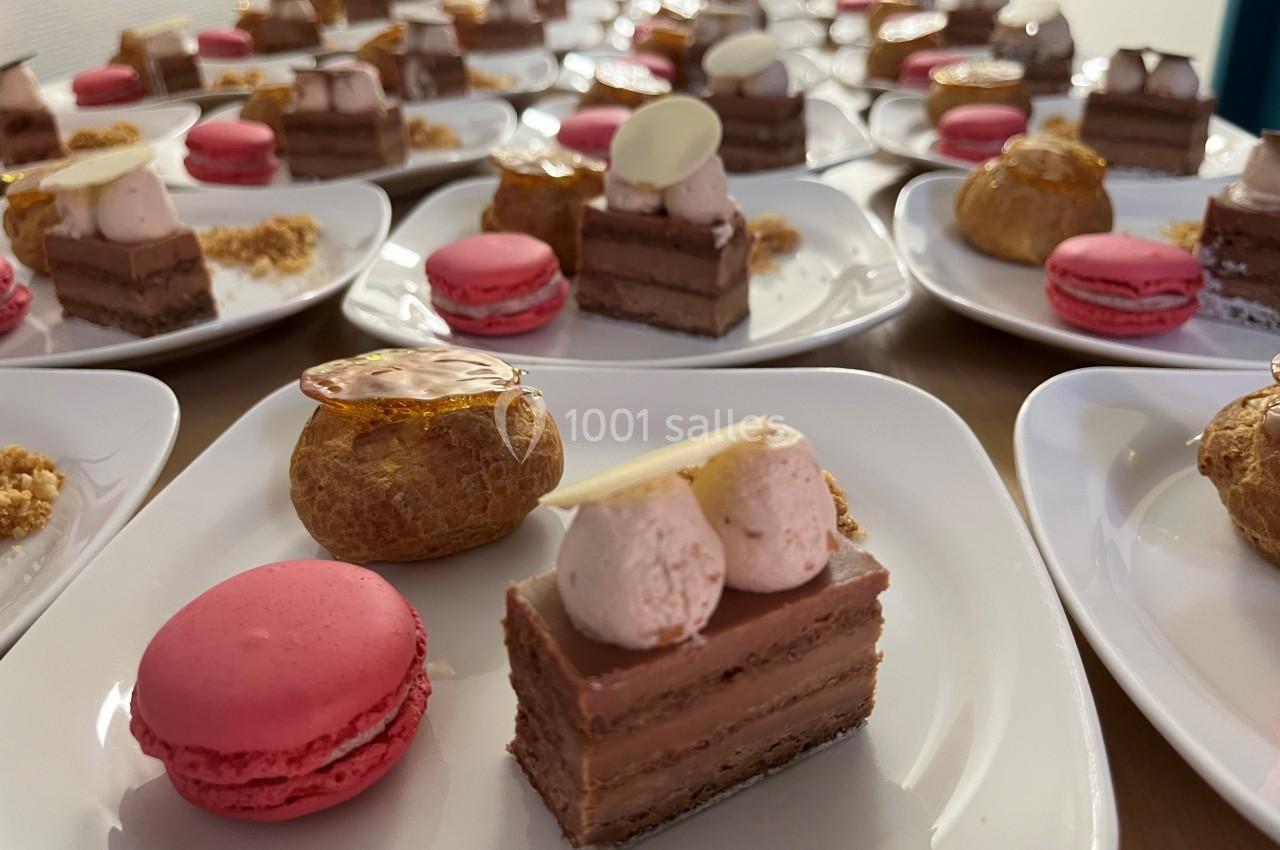 Assortiment de desserts individuels comprenant macarons, choux et gâteaux au chocolat sur des assiettes blanches.