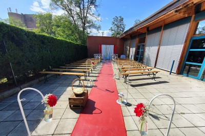 Vue d'une prairie verdoyante avec un grand arbre à gauche et des bâtiments ruraux sous un ciel dégagé.