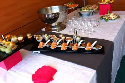 Vue d'une prairie verdoyante avec un grand arbre à gauche et des bâtiments ruraux sous un ciel dégagé.