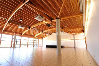 Vue d'une prairie verdoyante avec un grand arbre à gauche et des bâtiments ruraux sous un ciel dégagé.