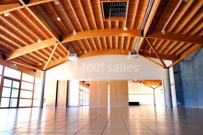 Vue d'une prairie verdoyante avec un grand arbre à gauche et des bâtiments ruraux sous un ciel dégagé.
