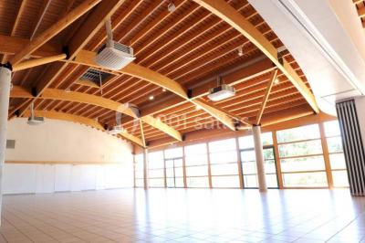 Vue d'une prairie verdoyante avec un grand arbre à gauche et des bâtiments ruraux sous un ciel dégagé.