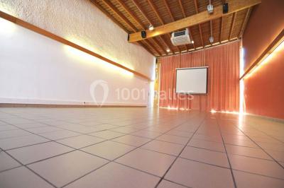 Vue d'une prairie verdoyante avec un grand arbre à gauche et des bâtiments ruraux sous un ciel dégagé.