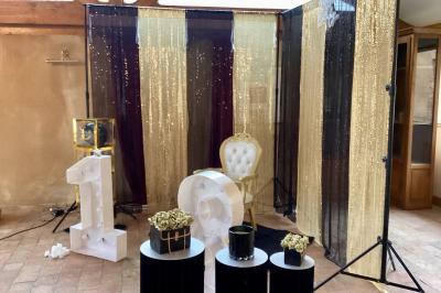 Salle à manger rustique avec table en bois dressée, mur en pierre apparente, étagères intégrées et cuisine ouverte.