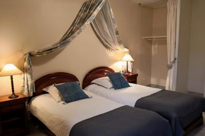 Salle à manger rustique avec table en bois dressée, mur en pierre apparente, étagères intégrées et cuisine ouverte.