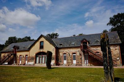 Salle à manger rustique avec table en bois dressée, mur en pierre apparente, étagères intégrées et cuisine ouverte.