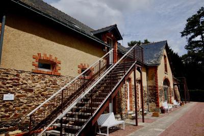Salle à manger rustique avec table en bois dressée, mur en pierre apparente, étagères intégrées et cuisine ouverte.