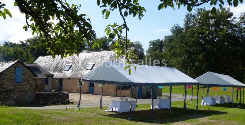 Tentes blanches installées dans un jardin près d'un bâtiment en pierre, sous un ciel dégagé.