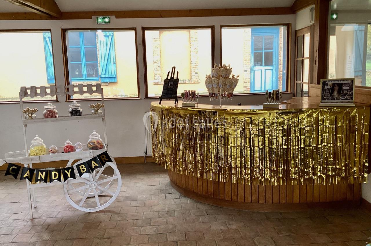 Chariot et comptoir décorés avec des friandises, guirlandes dorées et lumière naturelle dans une salle lumineuse.