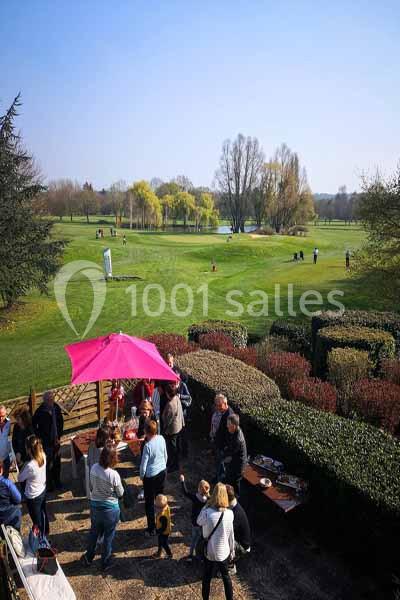 Groupe de personnes réunies sur une terrasse près d'un terrain de golf verdoyant par une journée ensoleillée.