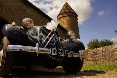 Deux voitures à pédales rétro sur un tapis rouge devant une tente tipi et un tableau noir dans un jardin.