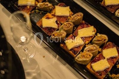 Chambre d'hôtel lumineuse avec lit double, coin salon, télévision murale et grandes fenêtres avec rideaux.