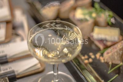 Chambre d'hôtel lumineuse avec lit double, coin salon, télévision murale et grandes fenêtres avec rideaux.