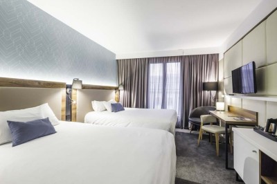 Salle de bain moderne avec lavabo, miroir éclairé, baignoire et murs en marbre.