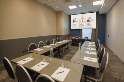 Salle de bain moderne avec lavabo, miroir éclairé, baignoire et murs en marbre.