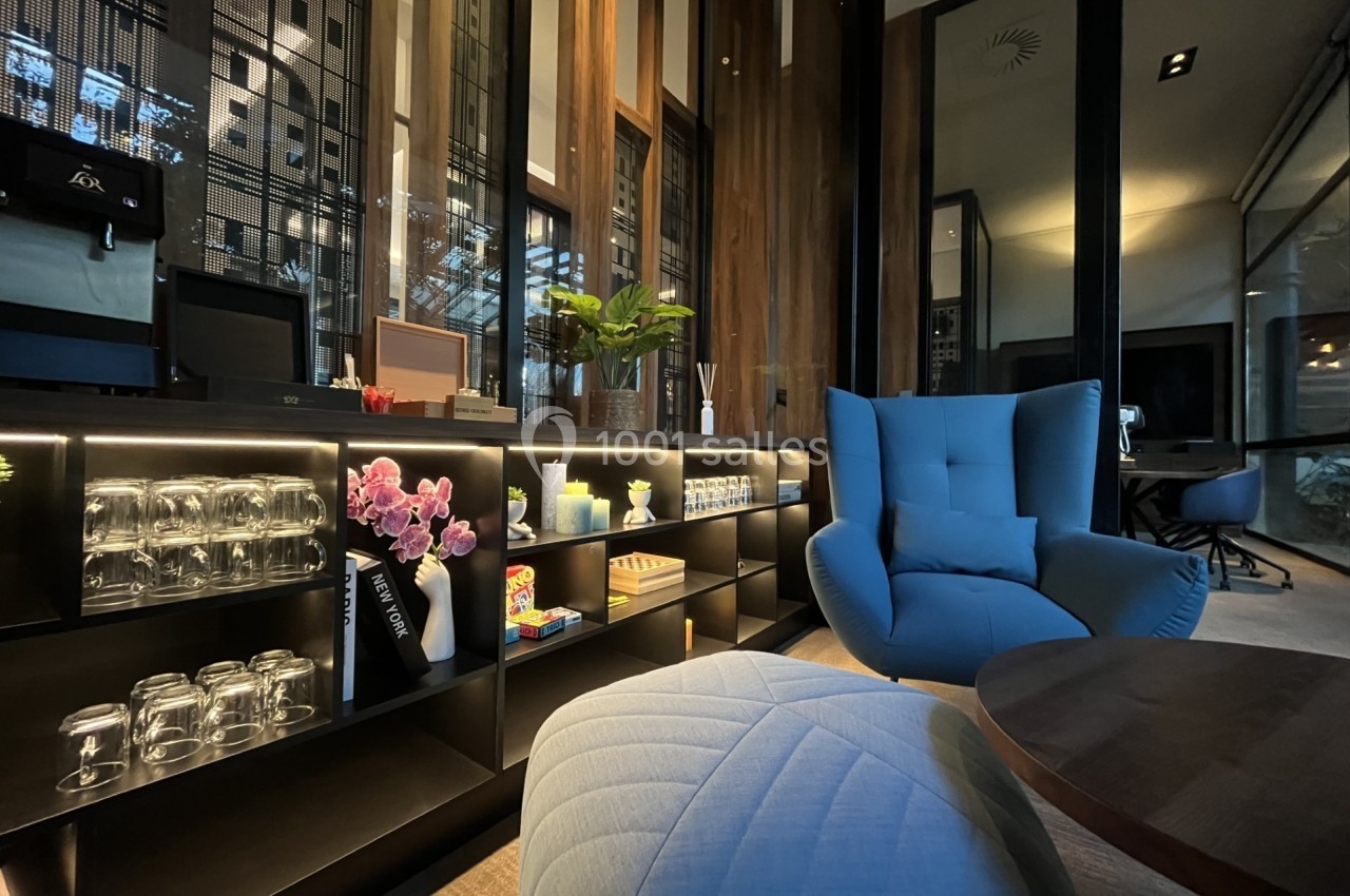 Espace intérieur moderne avec étagères éclairées, fauteuils confortables et décoration florale.