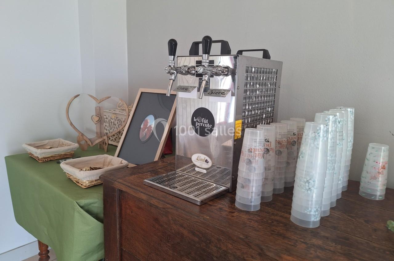 Distributeur de boissons avec gobelets en plastique empilés sur un meuble en bois, décoré d'éléments rustiques.