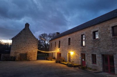Chambre lumineuse avec lit simple, commode verte, miroir, vase de pampas et fenêtre donnant sur un paysage verdoyant.