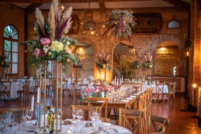 Chaises longues alignées devant un mur en pierre, entourées de grands arbres sous un ciel bleu clair.