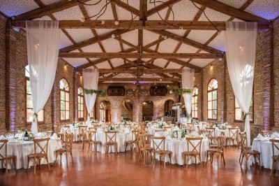 Chaises longues alignées devant un mur en pierre, entourées de grands arbres sous un ciel bleu clair.