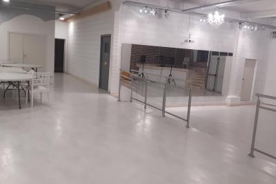 Salle lumineuse avec canapés, tables basses, bar moderne et décoration minimaliste, sous un plafond en verrière.